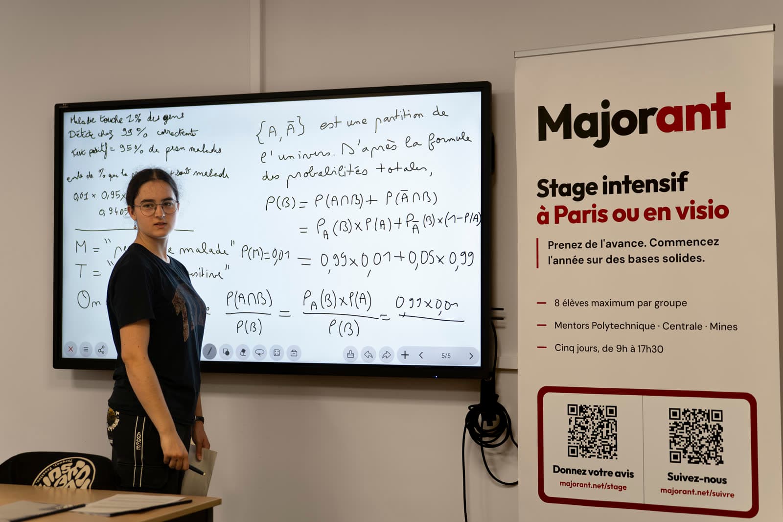 Un mentor présente un raisonnement au tableau, près d'un kakemono Majorant.